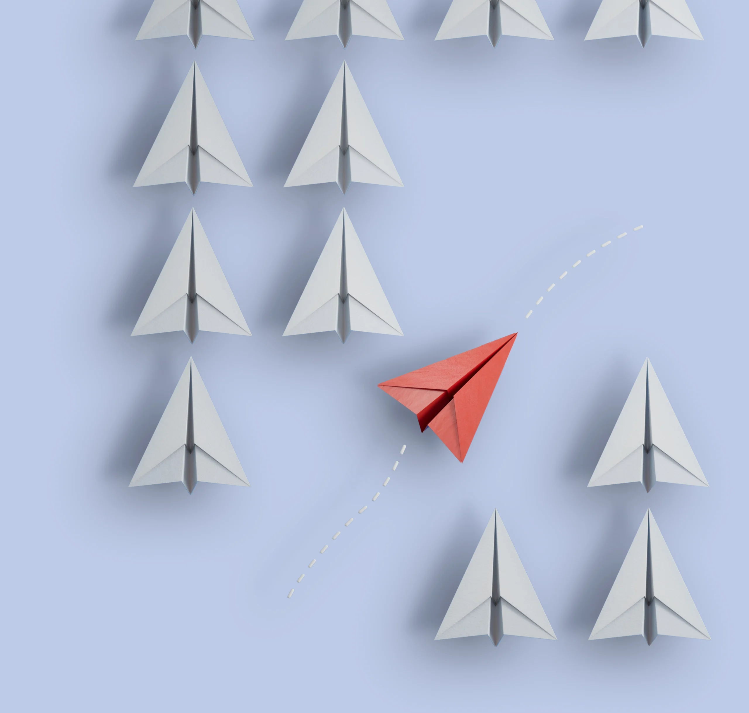 A red paper plane breaking away from rows of white ones
